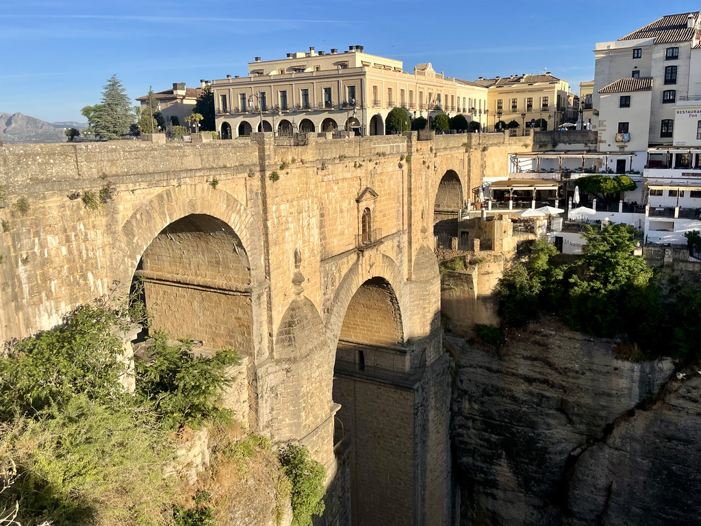 Puente Nuevo bridge viewed from street level in Ronda, with restaurant terraces beneath the arches.