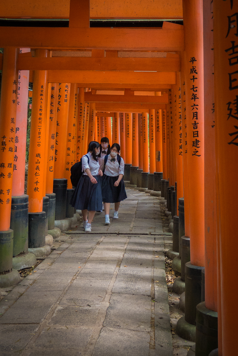 School girls walk through the iconic orange torii gates Fushimi-Inari Shrine