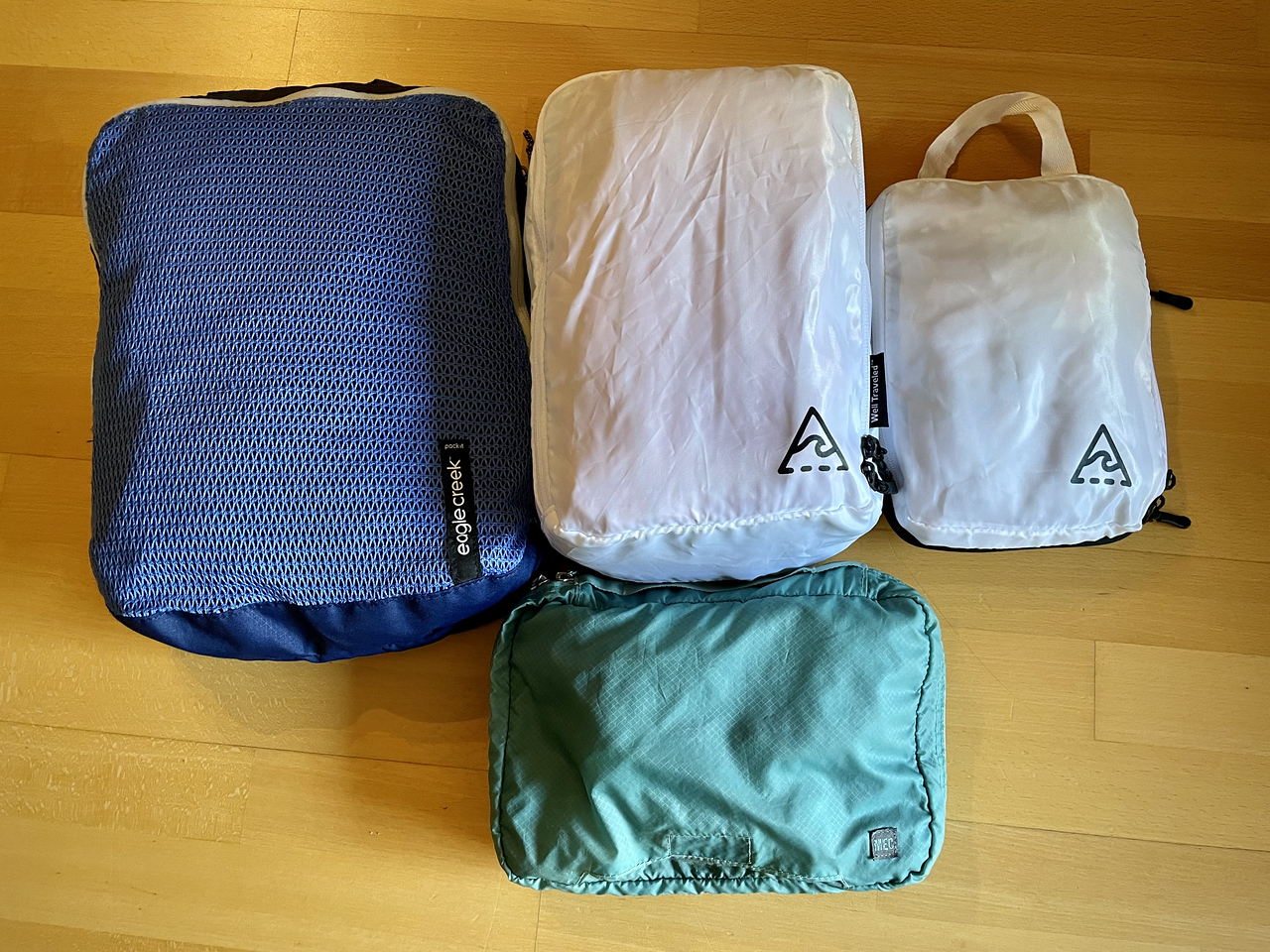 four packing cubes of various sizes and styles, including clean/dirty cubes, a toiletry kit, and a compression cube